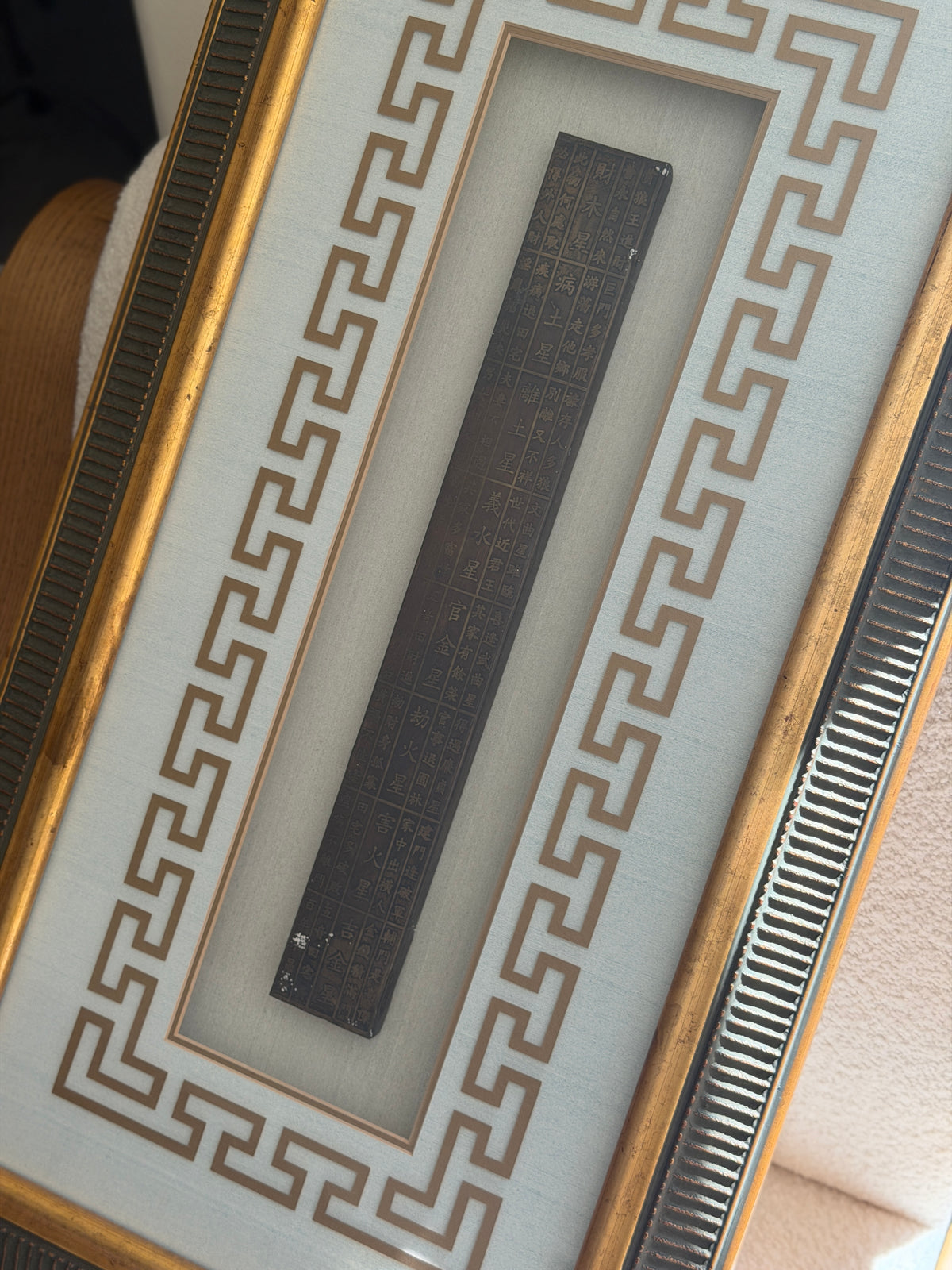 Close detail of the Lu Ban ruler showing columns of engraved Chinese characters arranged in a grid, framed by the gold key fret mat