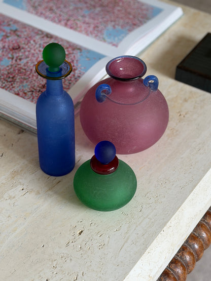 Franco Moretti green scavo vanity bottle with red glass collar and blue ball stopper, grouped with a blue bottle and pink amphora vase