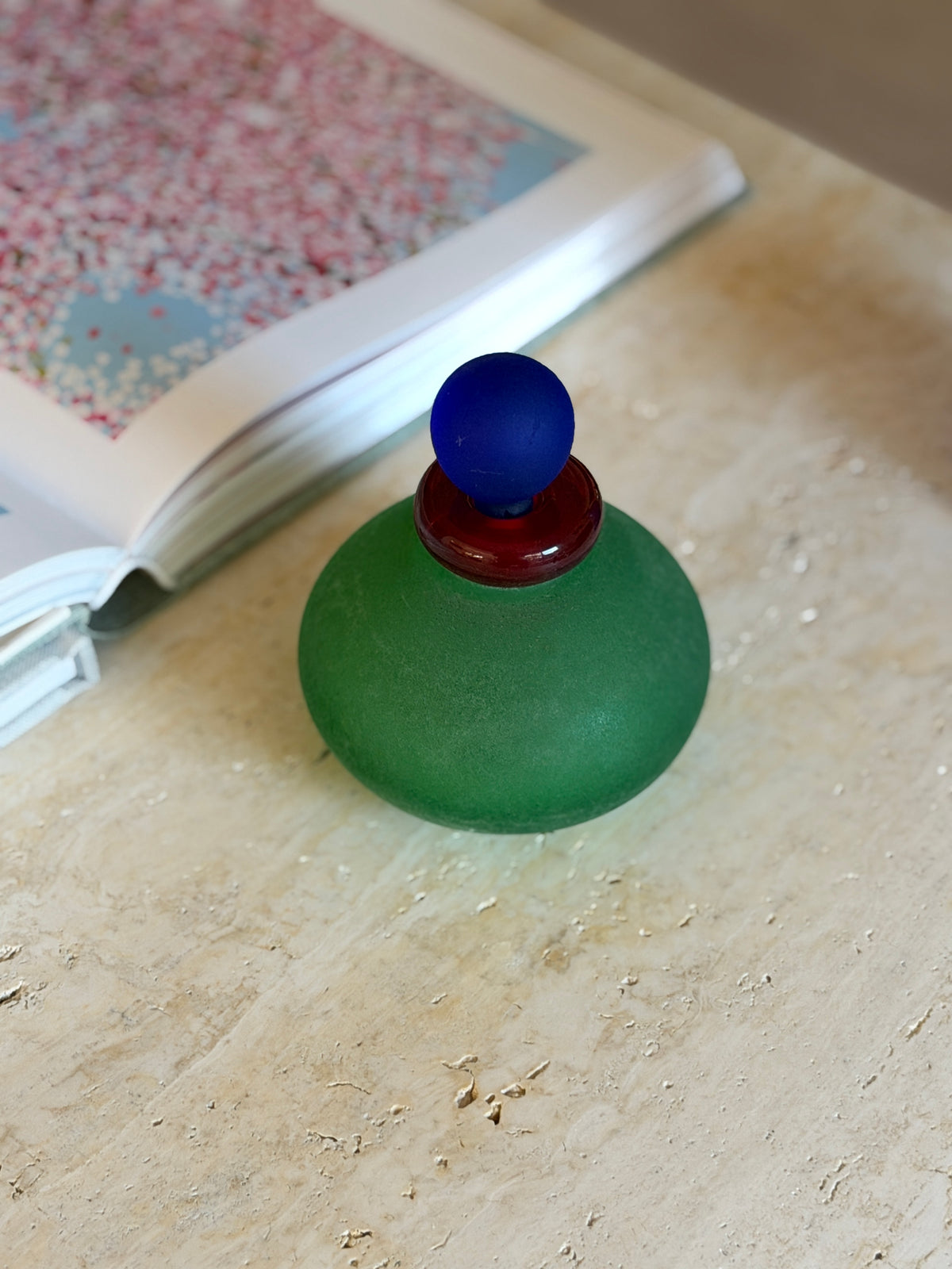 Overhead view of the green scavo bottle highlighting the ribbed red glass collar beneath the round blue stopper