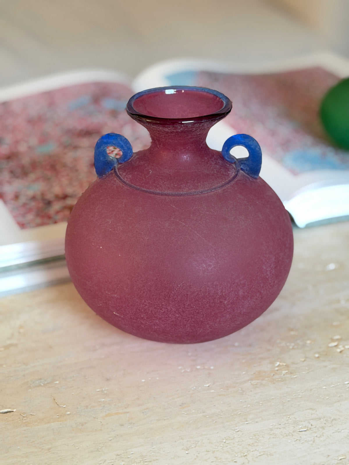 Close view of the pink scavo vase highlighting its rounded body, frosted texture, and curled blue glass handles
