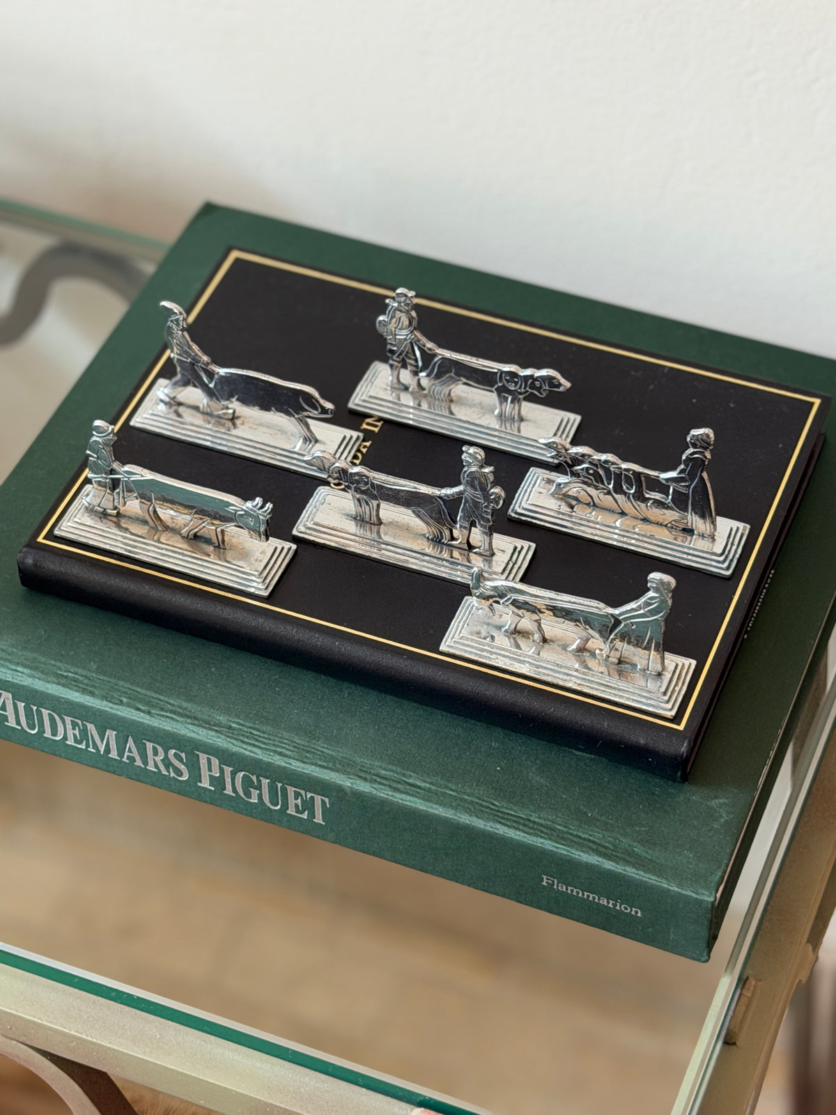 Full set of six French Art Deco knife rests displayed on a leather book