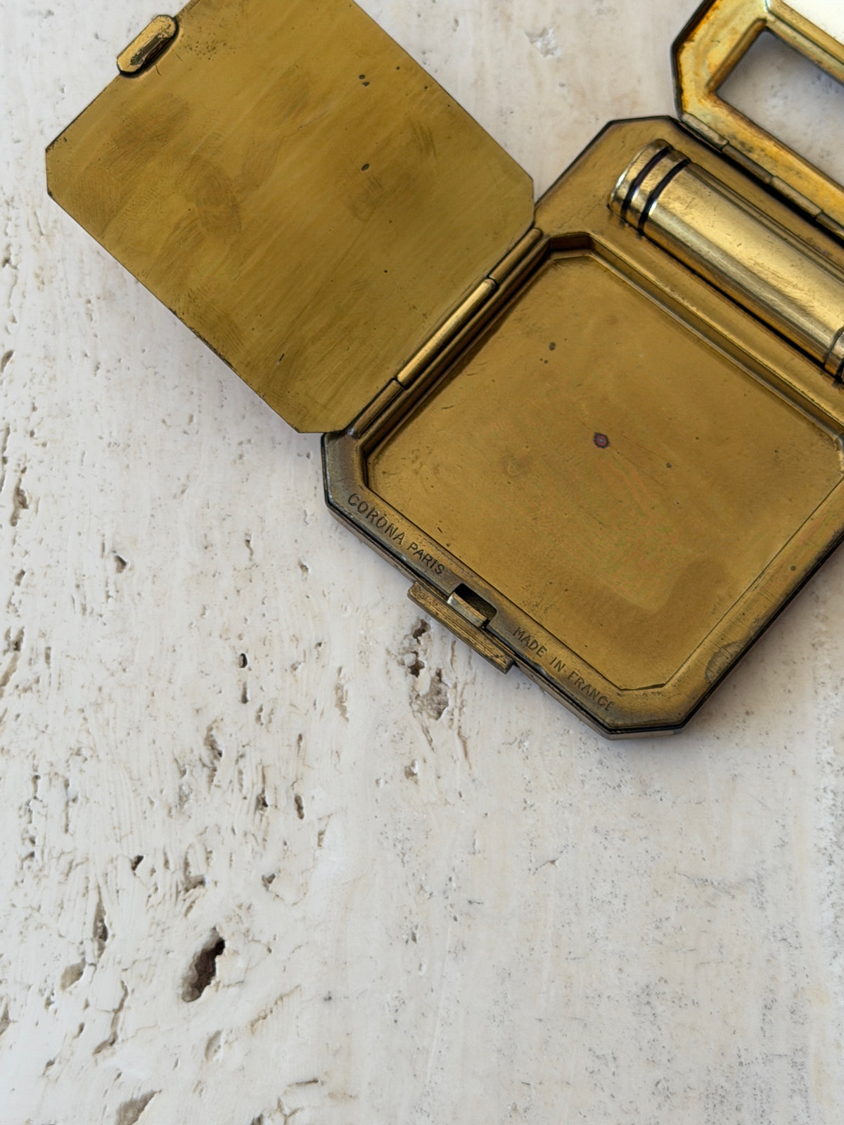 Close view of the compact interior rim stamped CORONA PARIS and MADE IN FRANCE beside the brass clasp