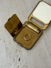 Open Corona Paris compact with a gold ring placed in the brass well to show scale, the mirror and lipstick tube above