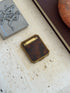 Closed tortoiseshell and brass compact on travertine beside a pewter box with athletes in relief and a red stone ashtray