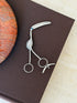 George Unite sterling silver flamingo sugar tongs with a long curved bill, engraved feathers, a turquoise eye, and ring handles, on a brown book