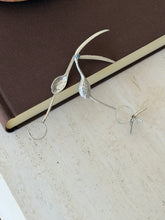 Flamingo tongs opened on a brown book, revealing the hidden spoon bowl inside the bill and the separate bird foot stand