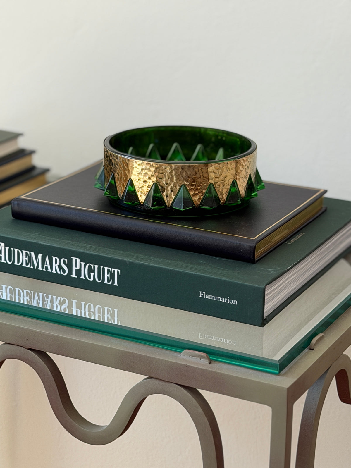 Angled view of mid-century green molded glass catchall dish with hand-hammered brass rim styled on books