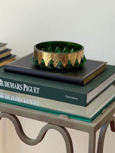 Angled view of mid-century green molded glass catchall dish with hand-hammered brass rim styled on books