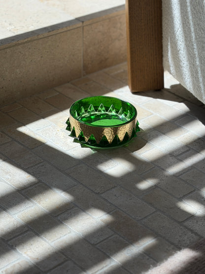 Collectors Gene vintage emerald green glass vide poche with hammered brass collar in natural sunlight on stone floor