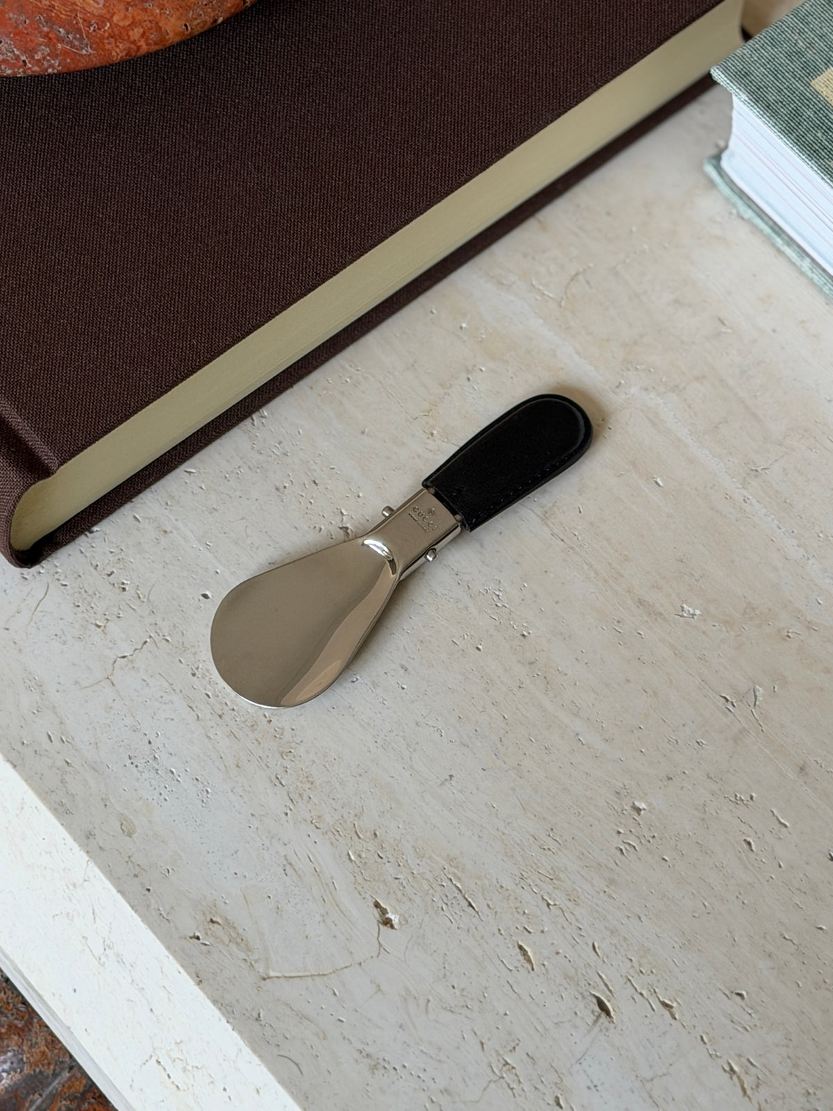 Folded Gucci shoehorn resting beside its brown monogram leather case