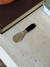 Folded Gucci shoehorn resting beside its brown monogram leather case