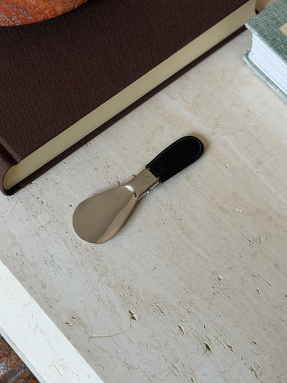 Folded Gucci shoehorn resting beside its brown monogram leather case