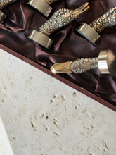 Close up of a gilt duck bill stamped GUCCI ITALY, the slotted beak designed to hold a name card