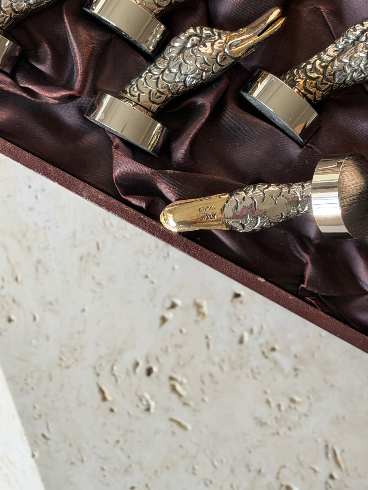 Close up of a gilt duck bill stamped GUCCI ITALY, the slotted beak designed to hold a name card