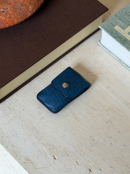 Angled view of the blue leather Gucci monogram case on a painted table surface