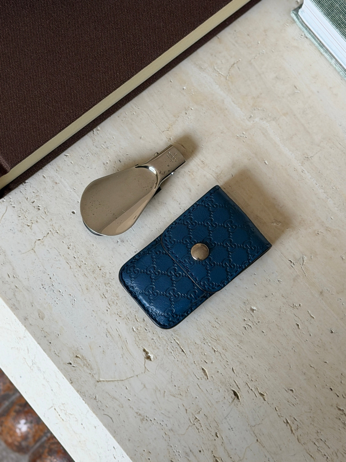 Gucci shoehorn folded next to its blue leather case