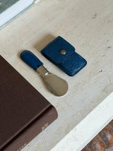Close-up of the side profile of the Gucci logo stamped on the blue leather shoehorn