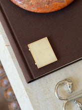 Another view of the closed frame on the book, with a horse-head bracelet visible nearby