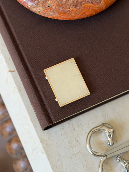 Another view of the closed frame on the book, with a horse-head bracelet visible nearby