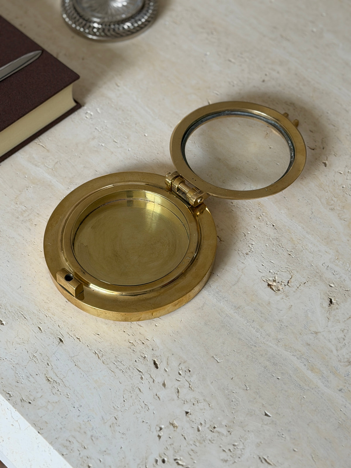 The porthole box shown open, its hinged glass panel lifted to reveal the brass interior