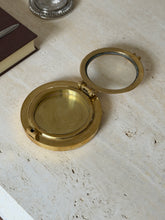 The porthole box shown open, its hinged glass panel lifted to reveal the brass interior