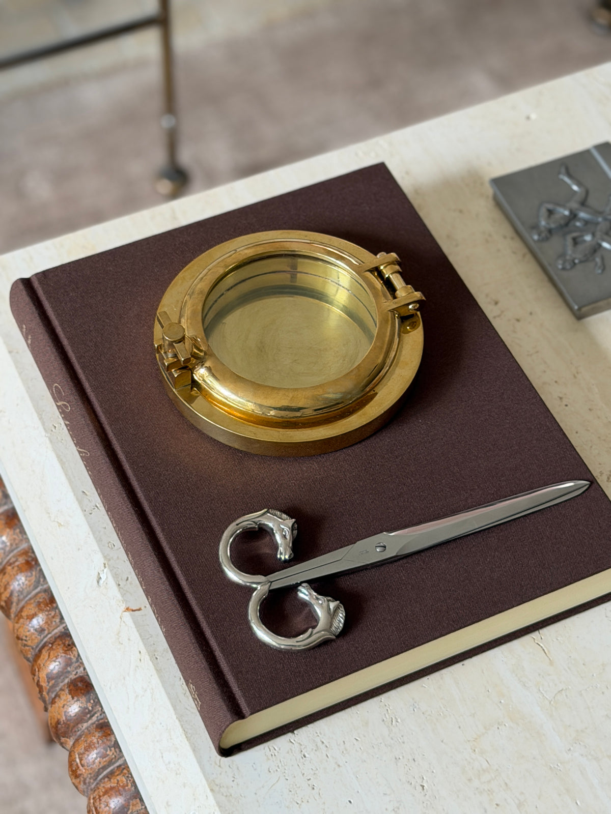The closed box displayed on a book alongside a silver horse-head letter opener and matching horse-head scissors