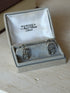 Pair of Hermes anchor chain link cufflinks seated in the gray suede presentation box, polished silver catching the light
