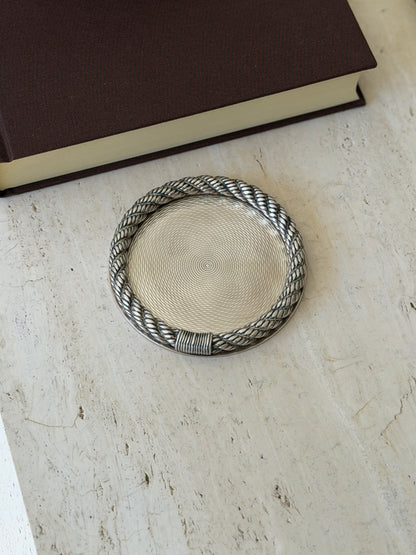 Hermes guilloche bottle coaster with a twisted cordage rope rim and wrapped binding, the center engine turned in concentric waves, on travertine