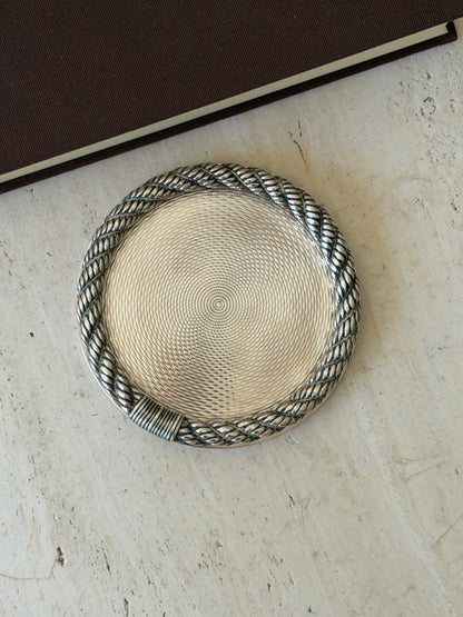 Close overhead view of the Hermes coaster, detailing the fine guilloche pattern and the ribbed rope binding at the base