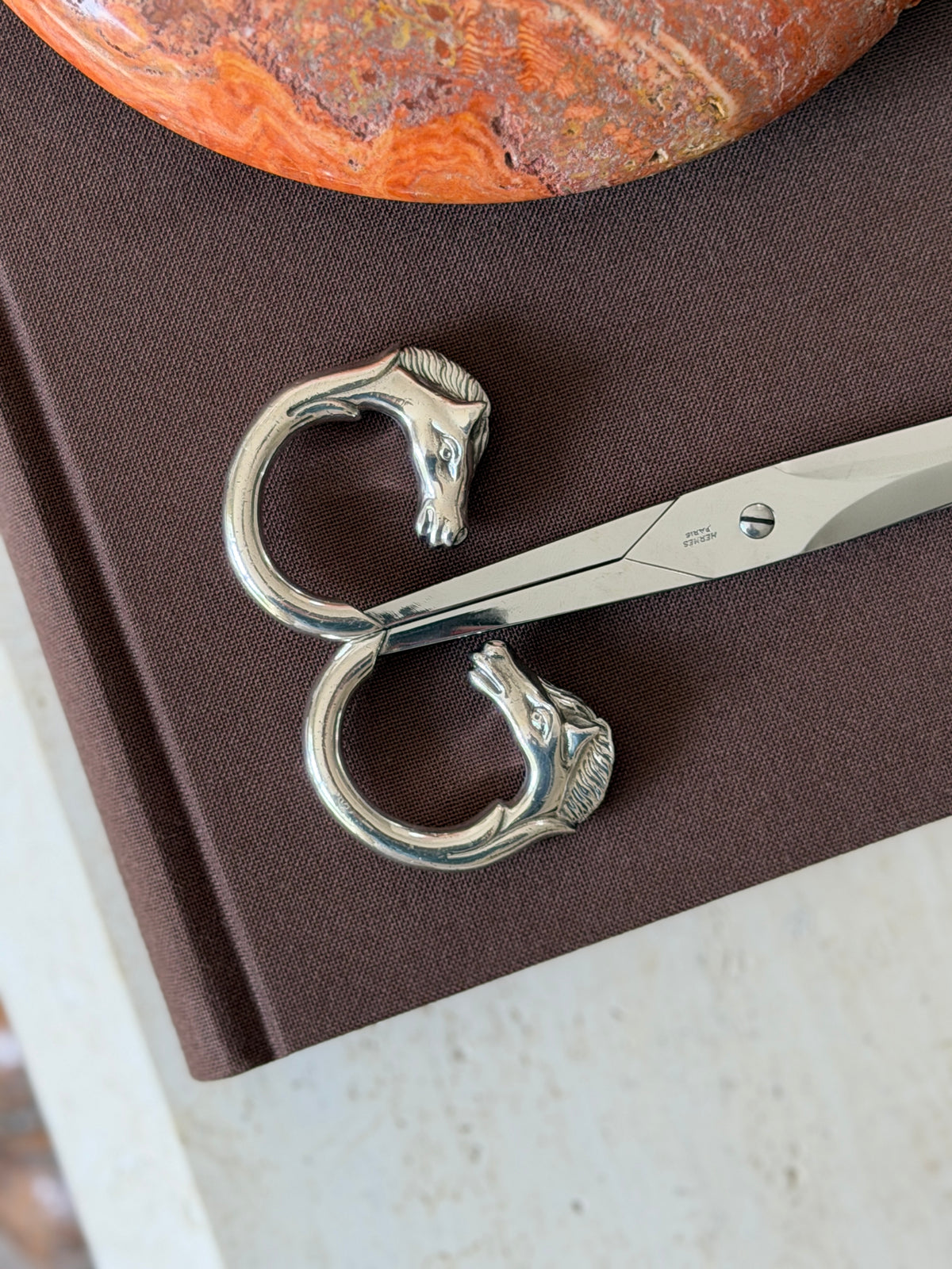 Close-up of the two horse-head handle rings forming a figure-eight shape, showing the detail of the mane and eyes