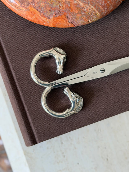 Close-up of the two horse-head handle rings forming a figure-eight shape, showing the detail of the mane and eyes