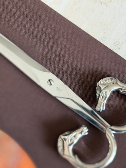 Extreme close-up of the blade near the pivot, showing the Hermes Paris engraving beside one horse-head handle