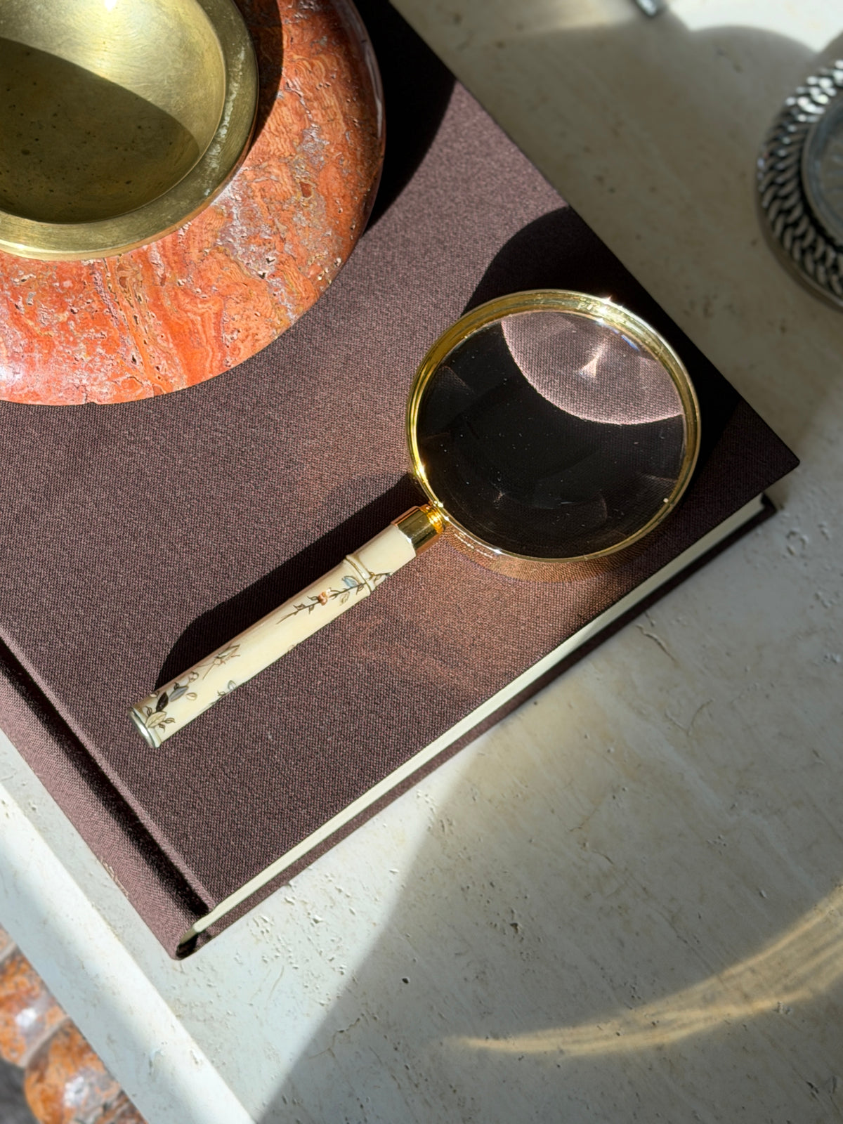 Top down view of the magnifier handle side showing the bamboo node carving, a small insect, and scattered leaves in gold and black