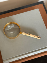 Reverse side of the Hermes magnifier handle, showing a carved bamboo node, an inlaid insect, and leafy branches against the cream ground