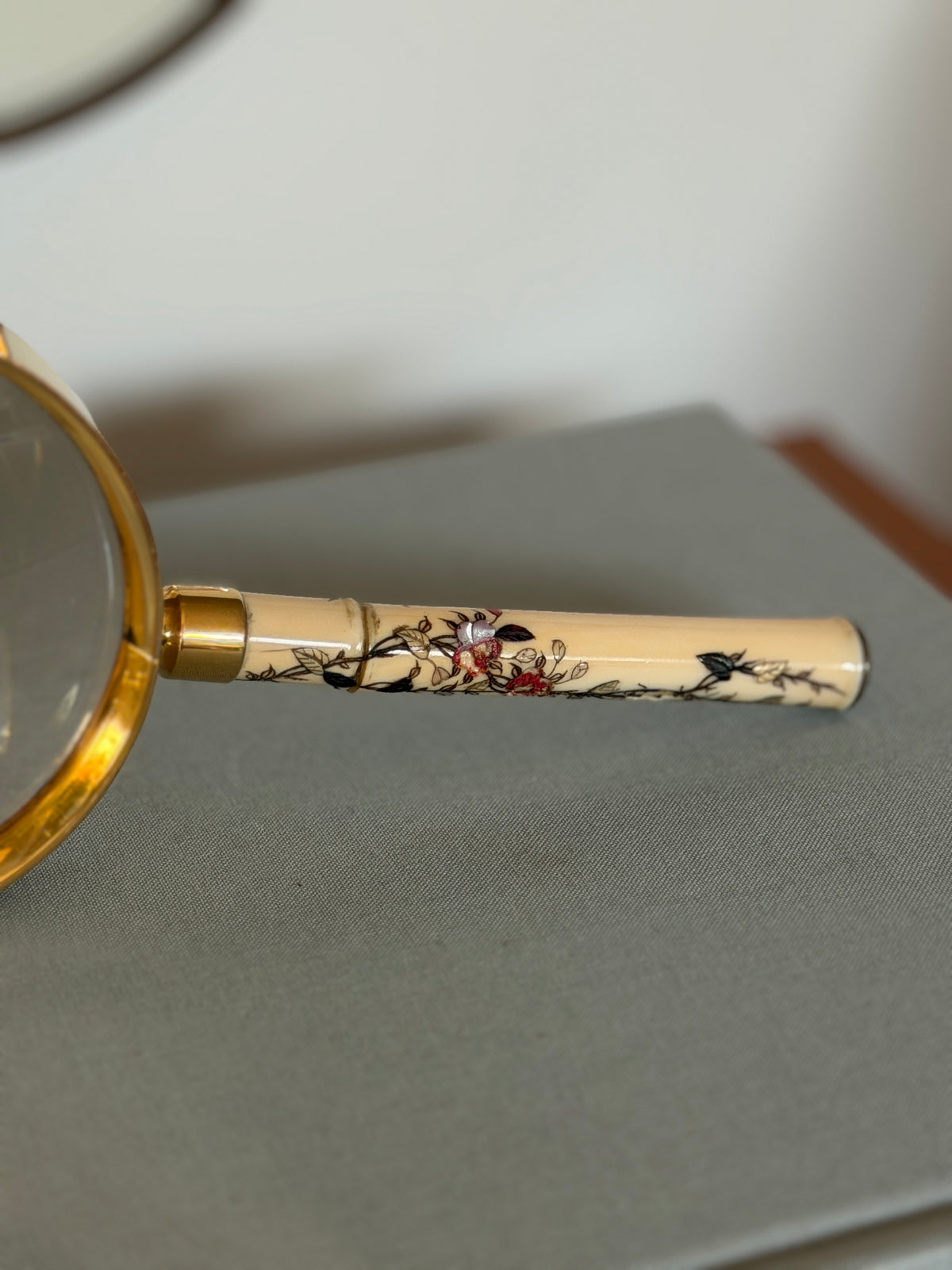 Side profile of the Meiji period handle, showing the inlaid blossoms, silver toned butterfly, and the gilt collar joining the lens frame