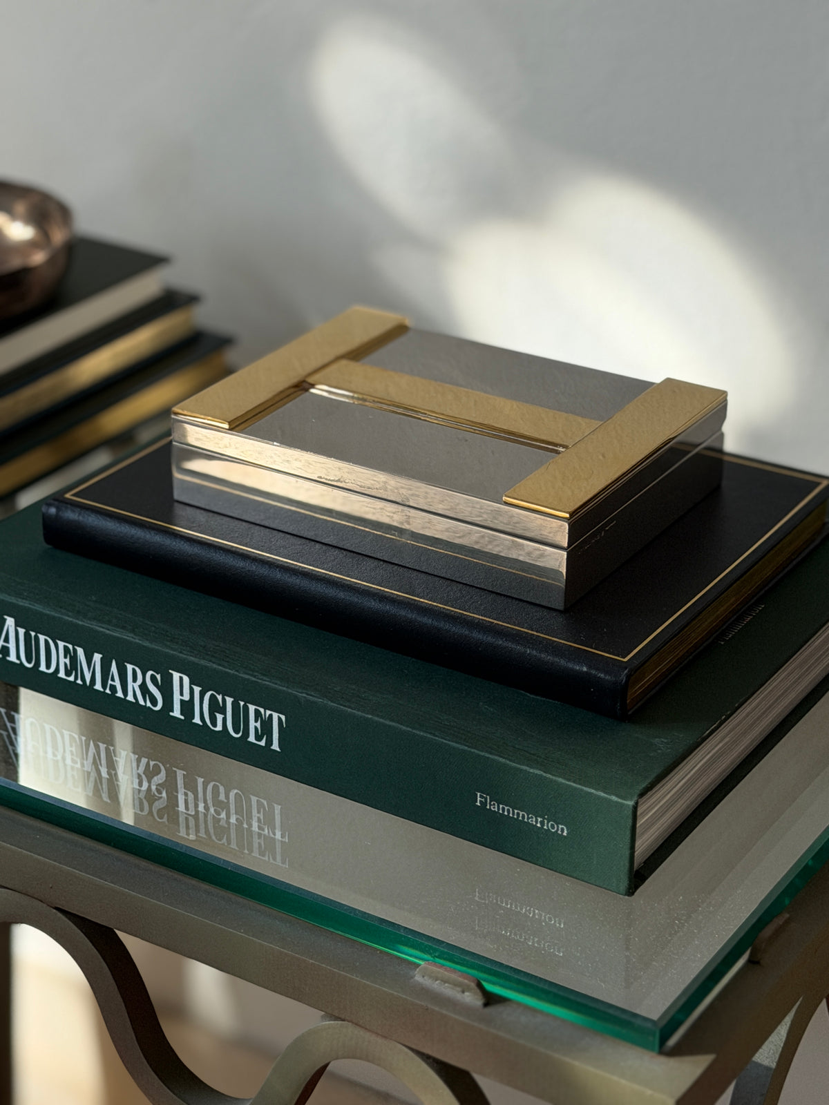 High angle view of closed Hermes silver and brass H logo box on book display available at Collectors Gene
