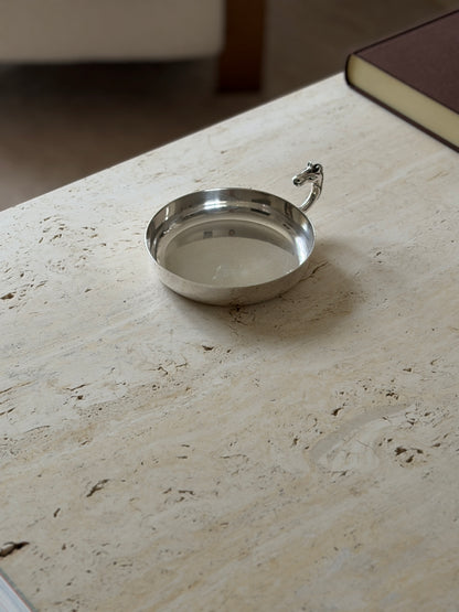 Horse head catchall on a travertine coffee table, styled with a silver lidded box with a red finial and a dark wood box