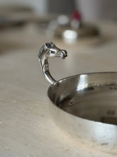 Close up of the sculpted horse head handle with detailed mane, eye, and flared nostrils, stamped marks inside the polished rim