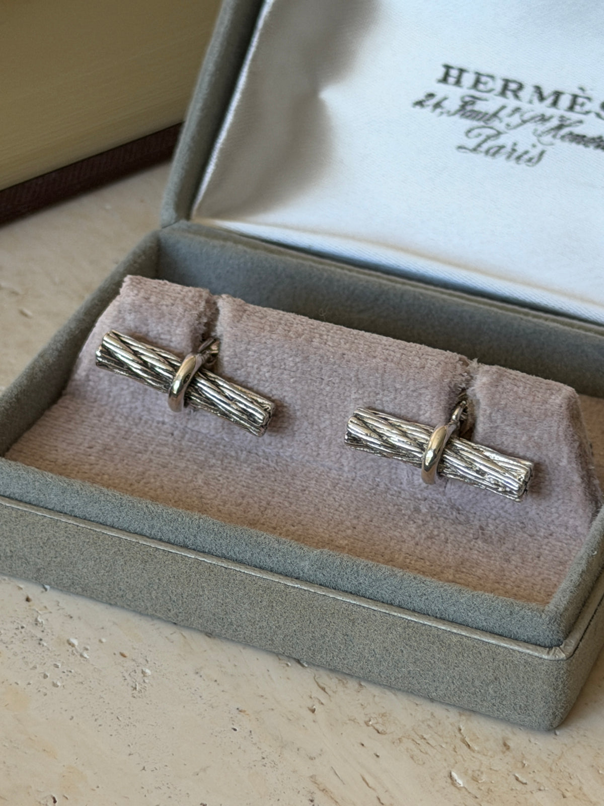 Closer view of the Hermes cable cufflinks in the box, showing the deeply textured twisted strands and polished wrapping band