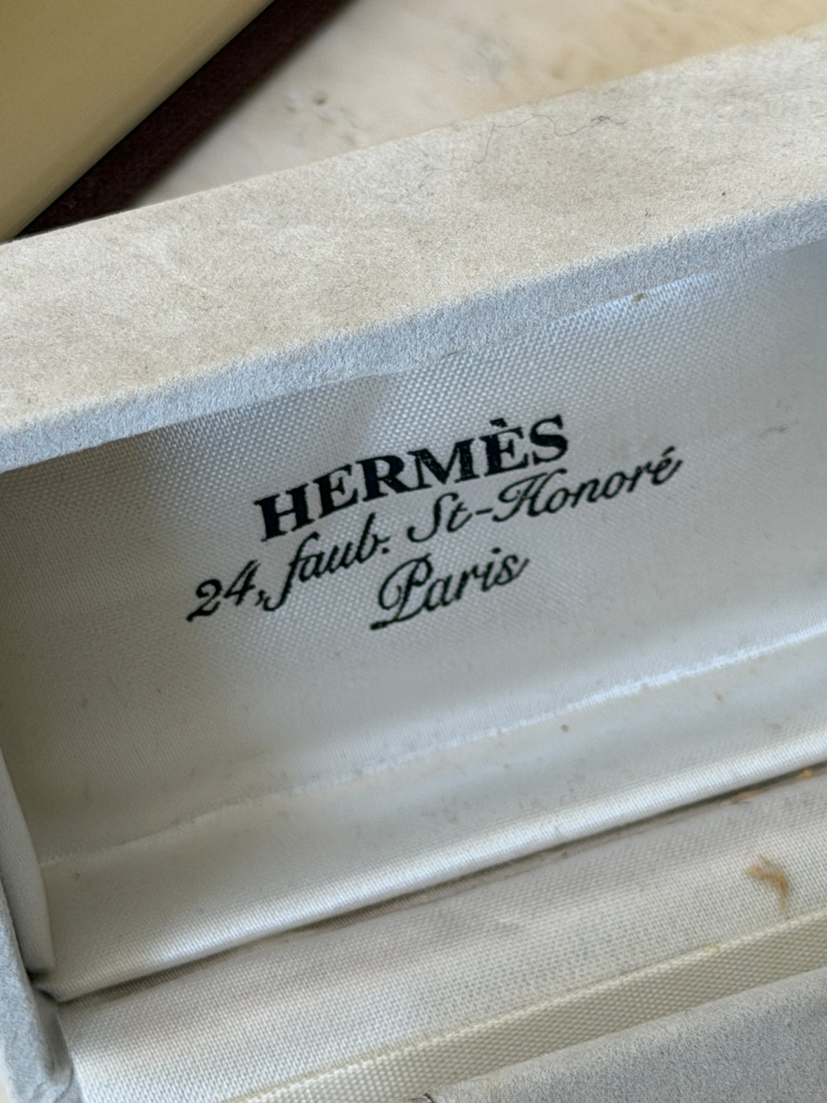 Close up of the satin lid lining printed Hermes 24 Faubourg Saint Honore Paris inside the pale gray suede cufflink box