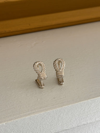 Hermes rope motif cufflinks side by side, each a teardrop loop of twisted rope bound by a ribbed silver wrapping