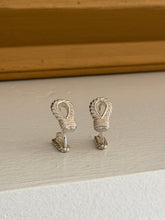 Front view of the Hermes rope loop cufflinks on a white ledge against a warm wood molding