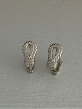Overhead view of the silver rope cufflinks, detailing the carved rope twist around each open loop and the banded knot