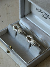 Hermes rope motif cufflinks seated in their pale gray suede box, the Paris address printed on the satin lid