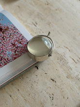 Close-up of the magnifier resting on the edge of an open book with a pink floral illustration, showing the spur handle in detail