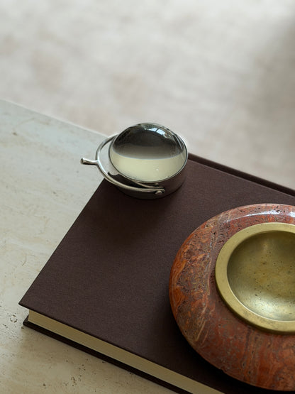The magnifier on the book beside the orange stone bowl with its brass insert