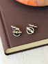 Silver ring and bar cufflinks on a brown linen book cover, showing the chain joining each front ring to its toggle back