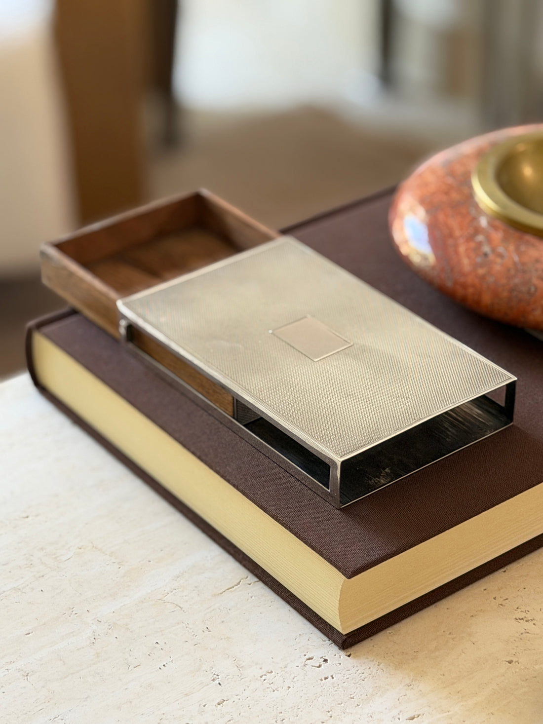 Angled view of the Hermes engine turned box showing the wood-edged slide tab mechanism
