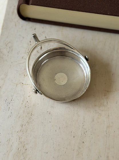 Overhead view of the Hermes sterling silver spur ashtray, the engine turned guilloche well circling a plain center disc inside a swinging hoop