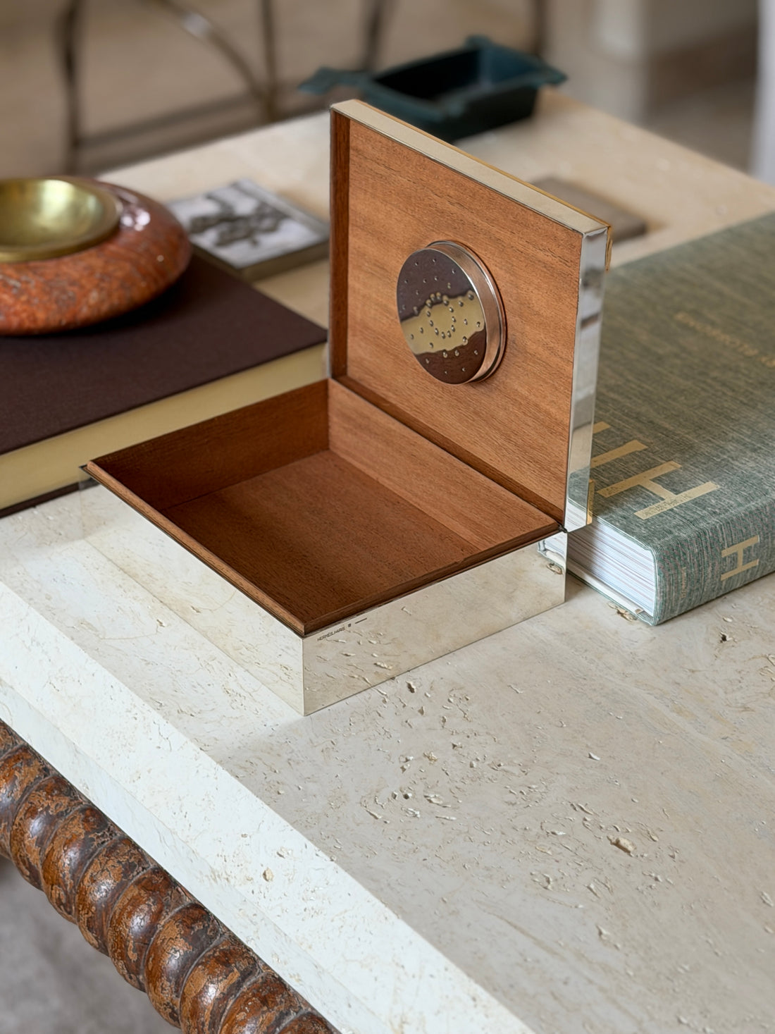Hermes humidor open on a marble surface, showing the wood interior and lid disc